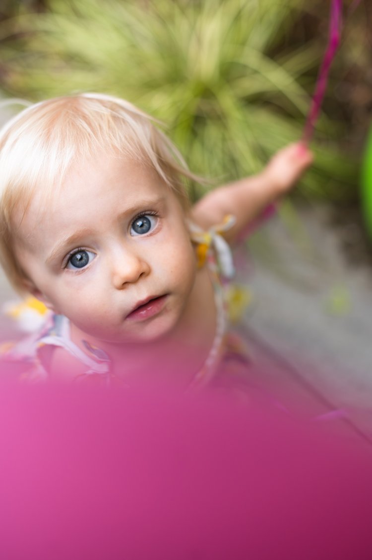 A cute baby girl with curious eyes gazed up at the camera in a heartwarming moment of a kid family photography.jpg