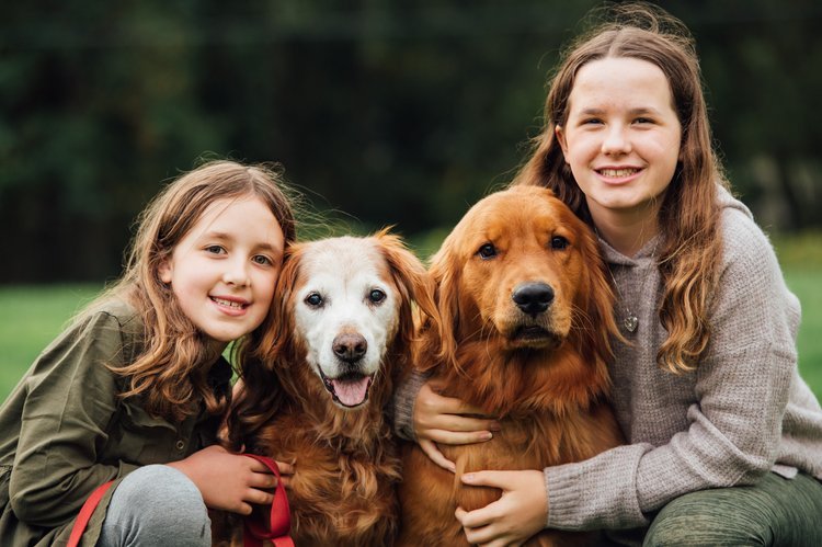 A family photography session captures two girls and a dog sitting on the grass.jpg
