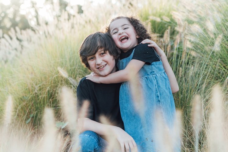 A serene family portrait showcasing a boy and girl seated in tall grass.jpg