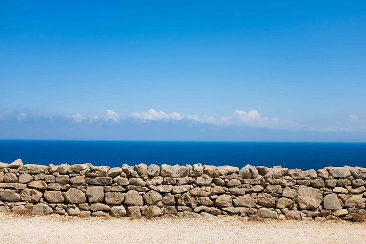 A captivating stone wall on the picturesque coast of Italy, captured by a travel photographer..jpg