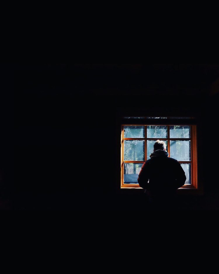 A photograph by Patrizia Montanari, A man standing in front of a window in a dark room.jpg