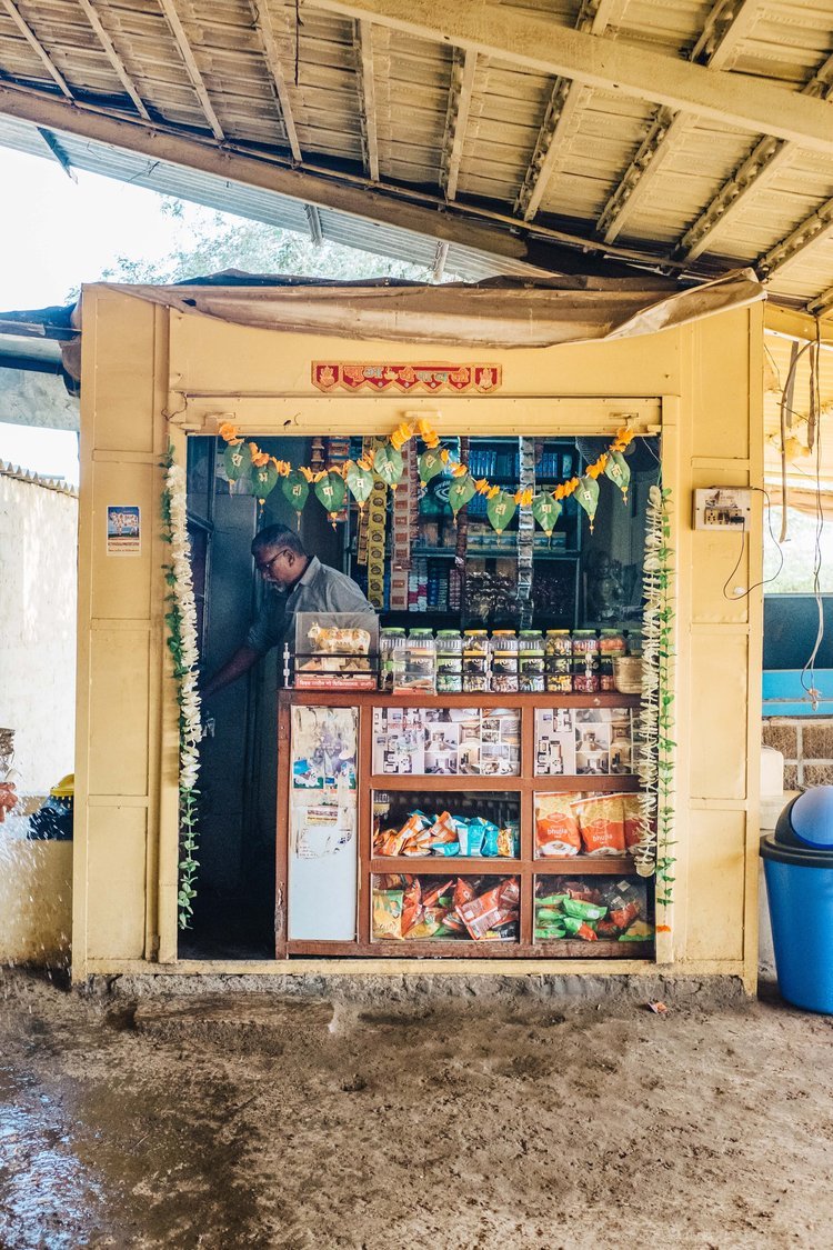 A travel photographer captures an image of a man standing in front of a store in a village with a sign.jpg
