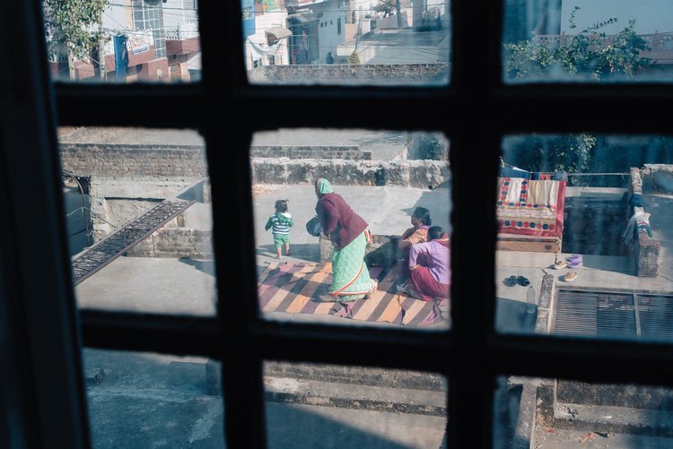 A travel photographer from Oregon captured a photo in India of a woman and child seen through a window on a roof representing the culture of India.jpg