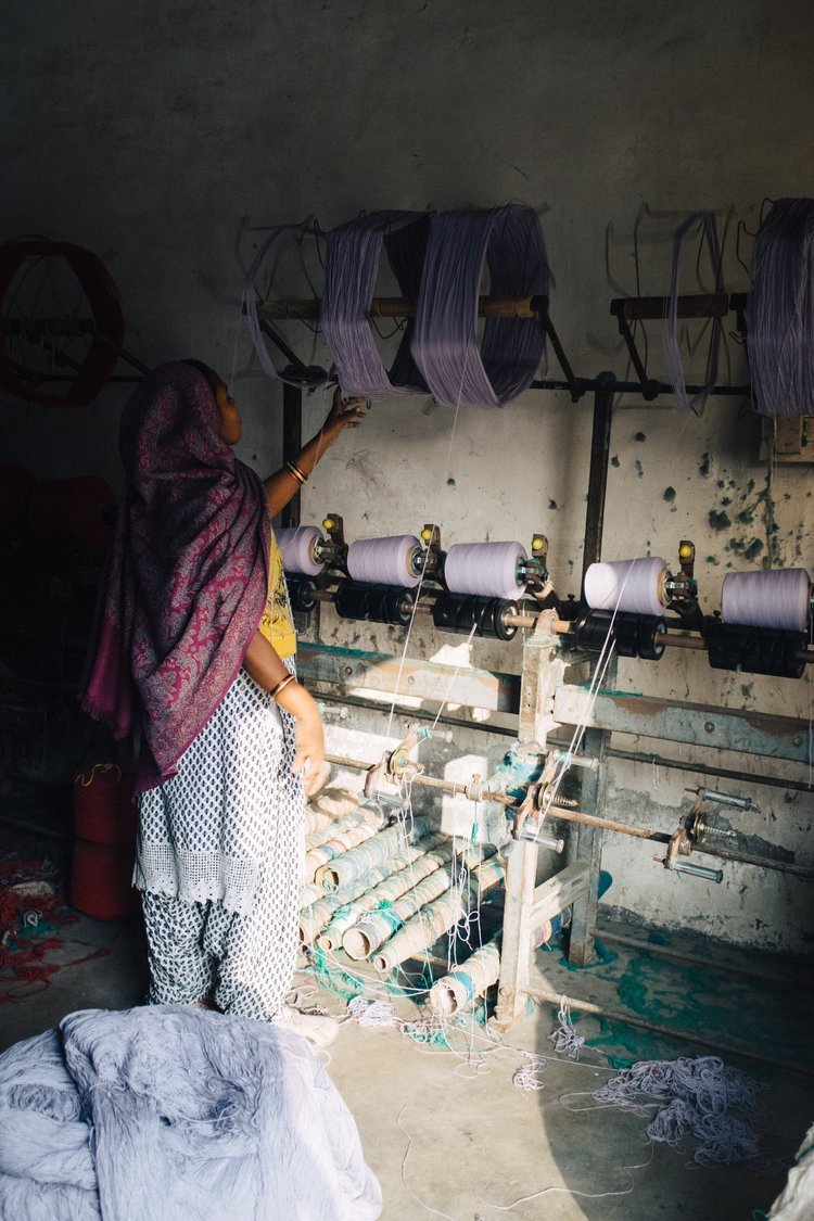 A woman operating a spinning machine in a room, captured by a Portland travel photographer in India.jpg