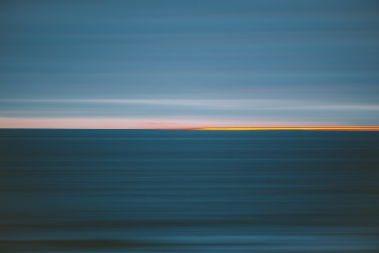 An abstract photograph capturing the serene beauty of the ocean at sunset, with vibrant colors and a tranquil atmosphere..jpg