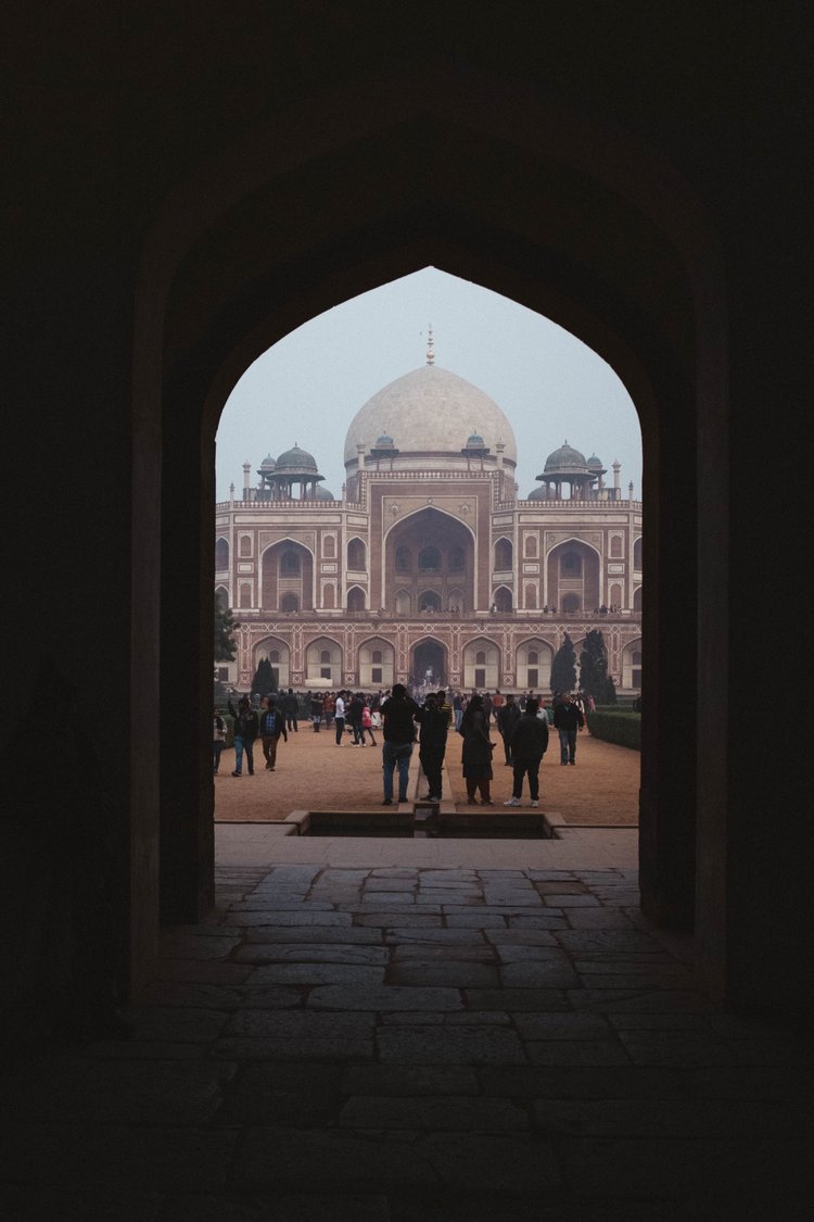 Individuals are strolling beneath an archway situated in front of a building in India.jpg