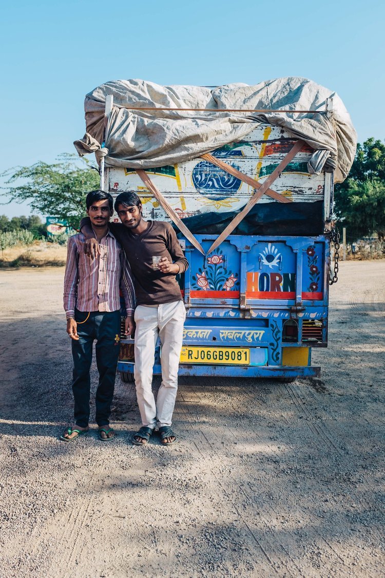 Two men standing next to a truck in the dirt, captured by a renowned travel photographer from Portland.jpg