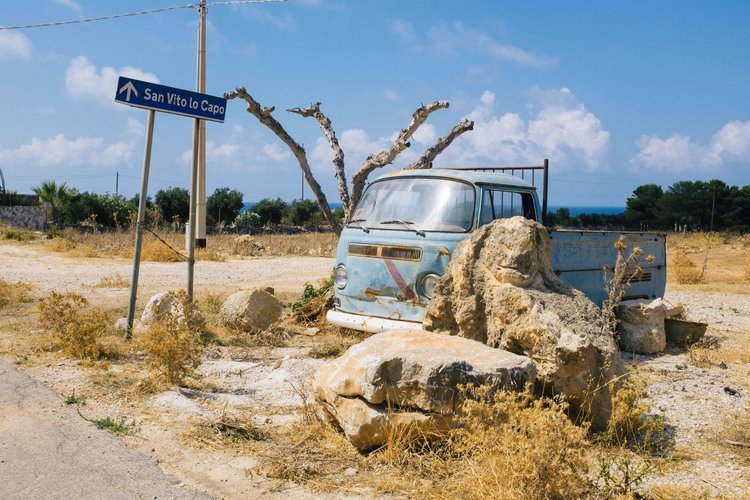 An old carry truck parked on a dirt road near the road sign of san vito la capo captured by Patrizia a Travel Photographer from portland.jpg