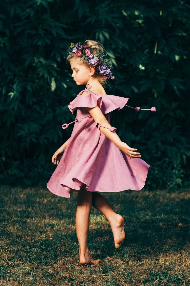 A charming image of a little girl wearing a pink dress, joyfully exploring the grassy surroundings - a delightful children's photography.jpg