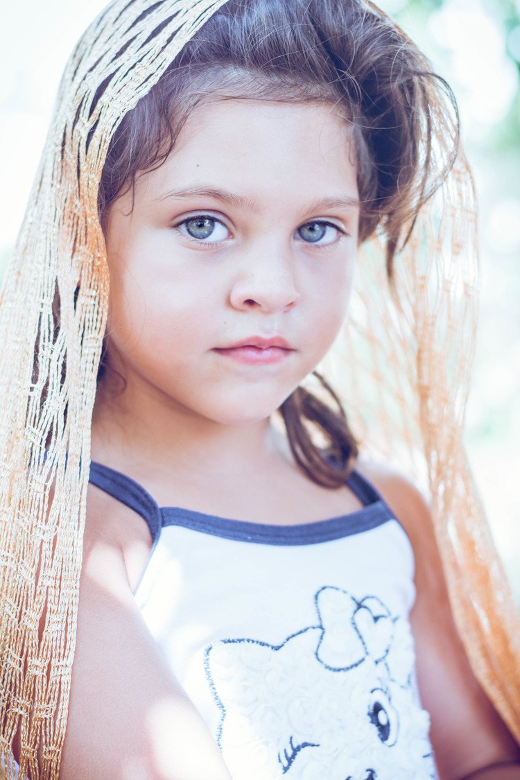 A child portrait featuring a young girl with a long stylish net scarf on her head.jpg