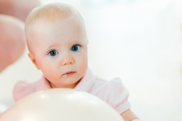 A newborn baby captivated by a white ball in a delightful moment.jpg