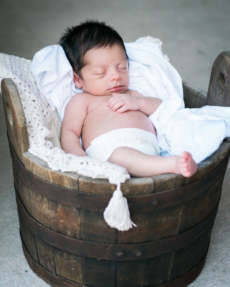 A peaceful newborn kid sleeping soundly in a wooden bucket.jpg