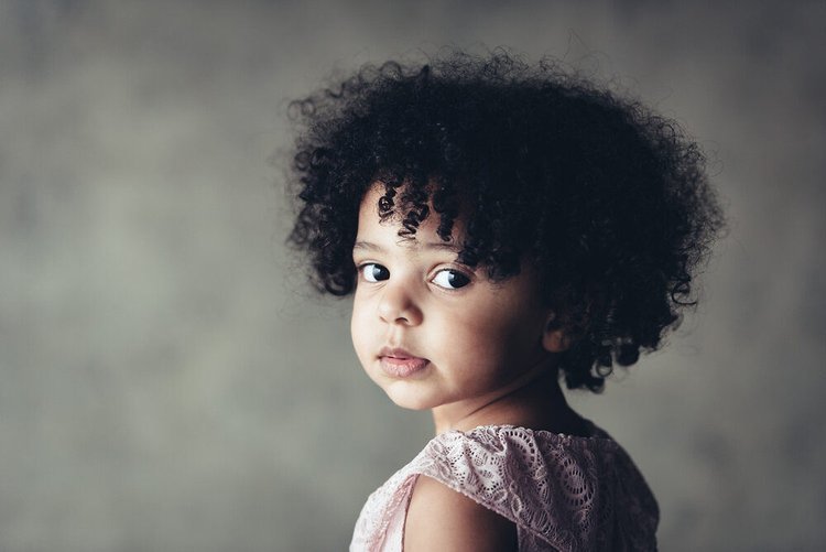A Portland children's photographer captured a young girl with curly hair looking at the camera.jpg