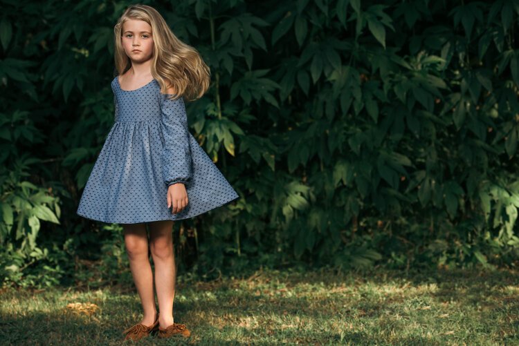 A young girl in a blue dress poses in the grass, photographed by a children photographer in Portland, Oregon.jpg