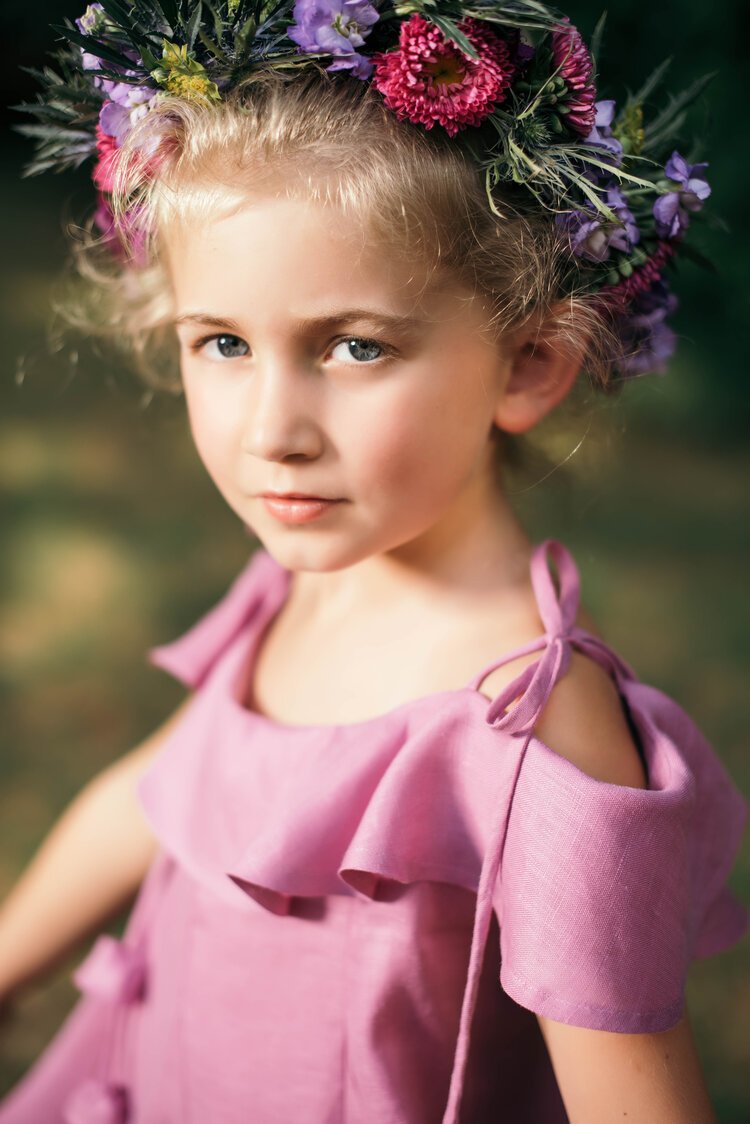 A young girl joyfully adorns a delicate flower crown, radiating innocence and beauty.jpg