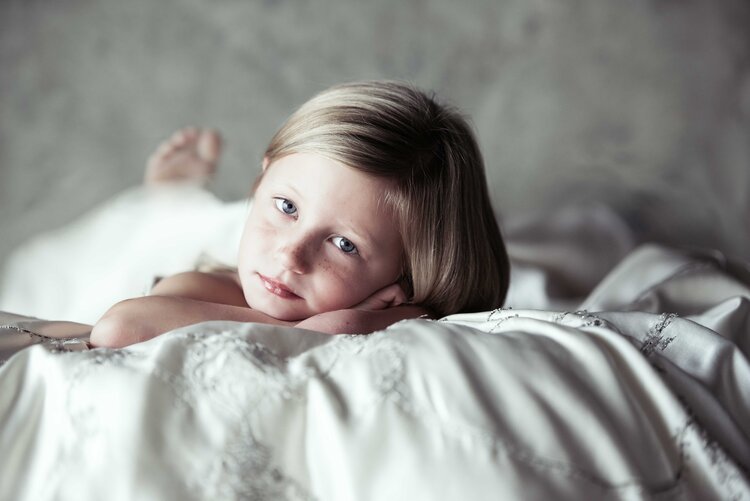 A young girl peacefully resting on a bed and posing.jpg