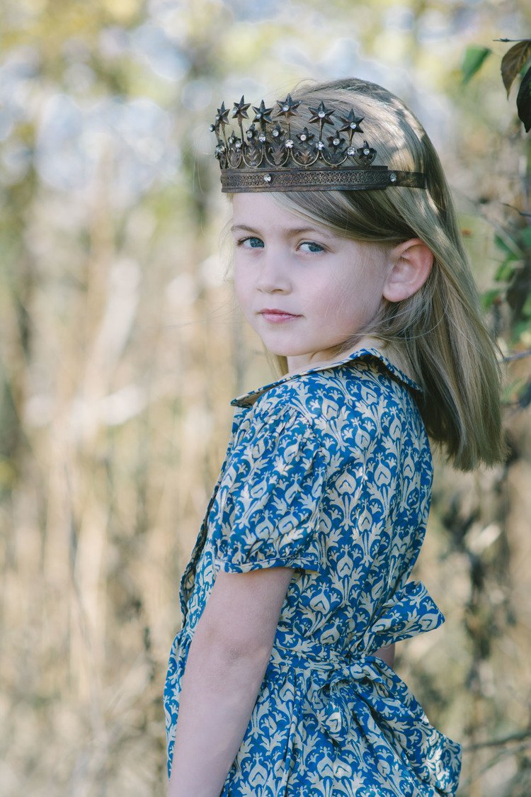 A young girl wearing a crown in a forest. A charming image capturing the innocence and wonder of childhood in nature.jpg