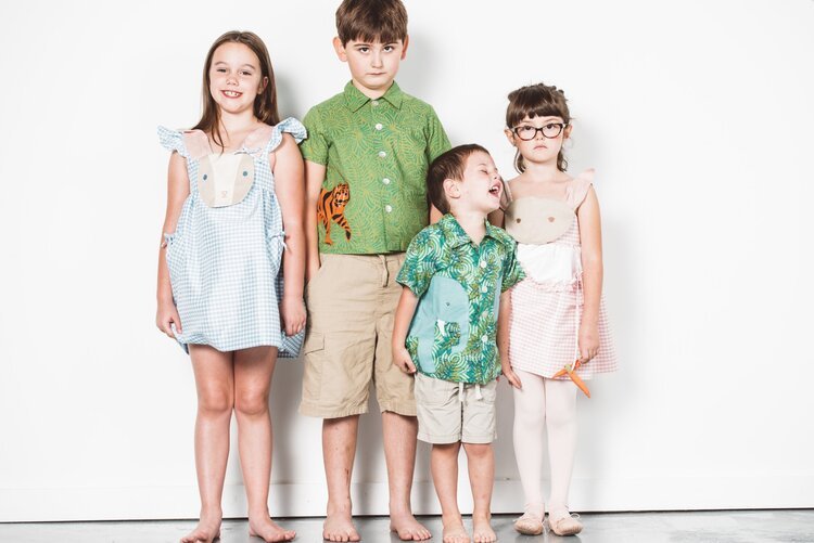 Four children posing in front of a white wall for a kids photography session.jpg
