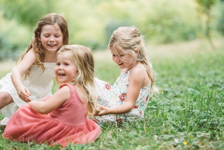 Three little girls playing happily in the grass.jpg