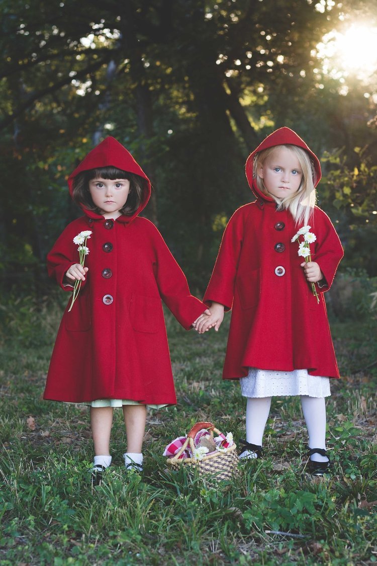 Two girls in red coats, holding hands, photographed by a children's portrait photographer.jpg