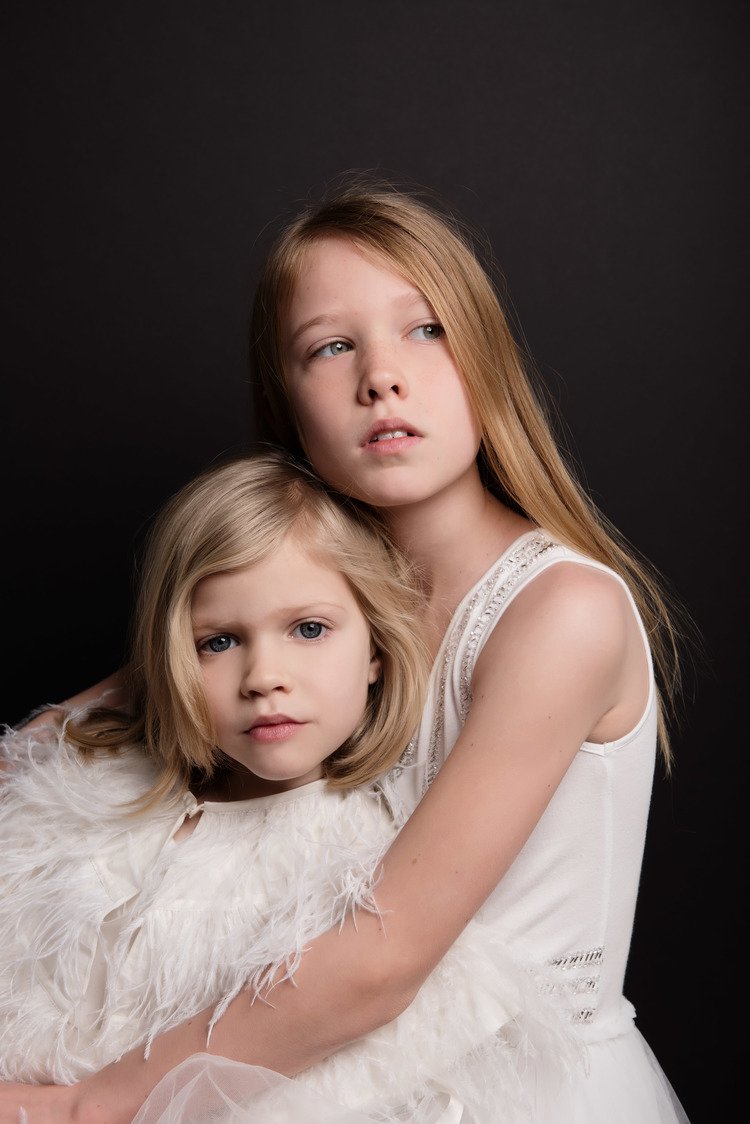Two girls in white dresses embracing each other posing for children photography shoot.jpg