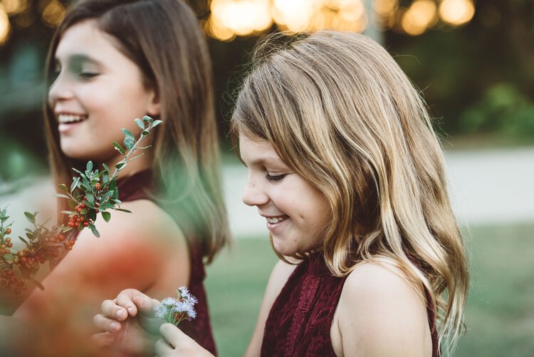 Two joyful little girls holding flowers and smiling.jpg