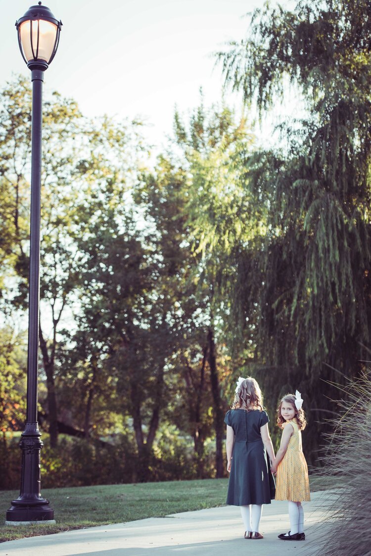 Two little girls in dresses walking down a path, captured by a children photographer in Portland.jpg