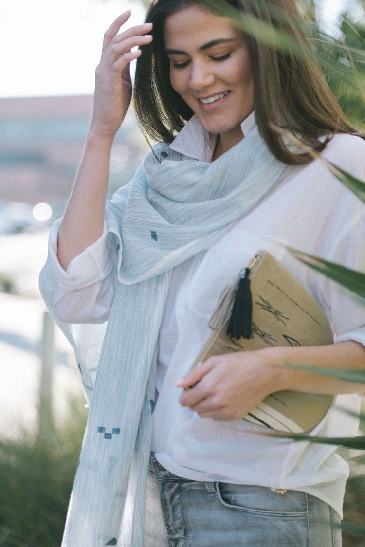 An image of a woman elegantly dressed in a white shirt and adorned with a blue scarf, in a lifestyle photograph.jpg