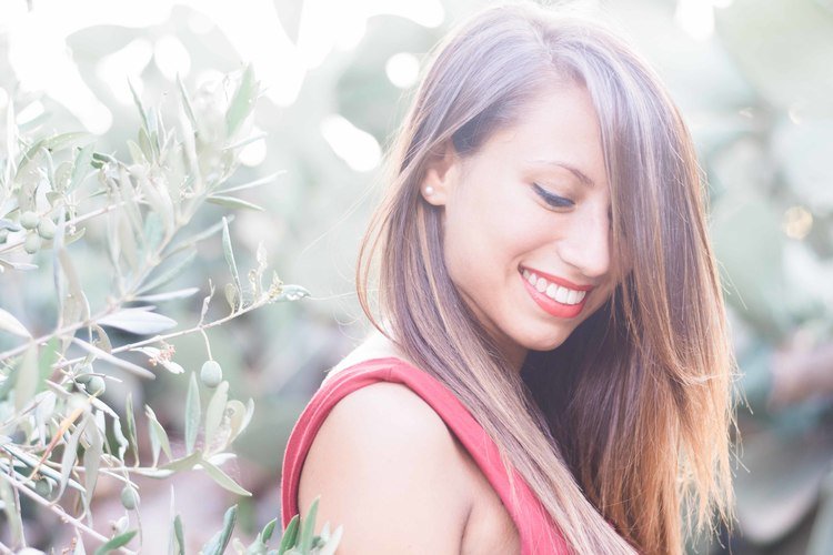 In a fashion lifestyle photography, a woman with long hair smiles gracefully among lush plants.jpg
