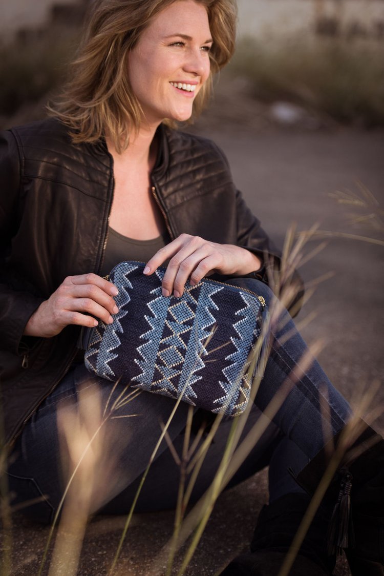 Lifestyle photography of a woman sitting on the ground, holding a blue and white purse.jpg