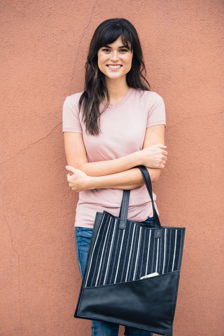 This captivating lifestyle image showcases a woman confidently holding a black-and-white striped tote bag.jpg