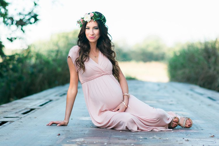 A beautiful pregnant woman, dressed in pink, finds solace on a bridge during a lifestyle maternity photography shoot.jpg