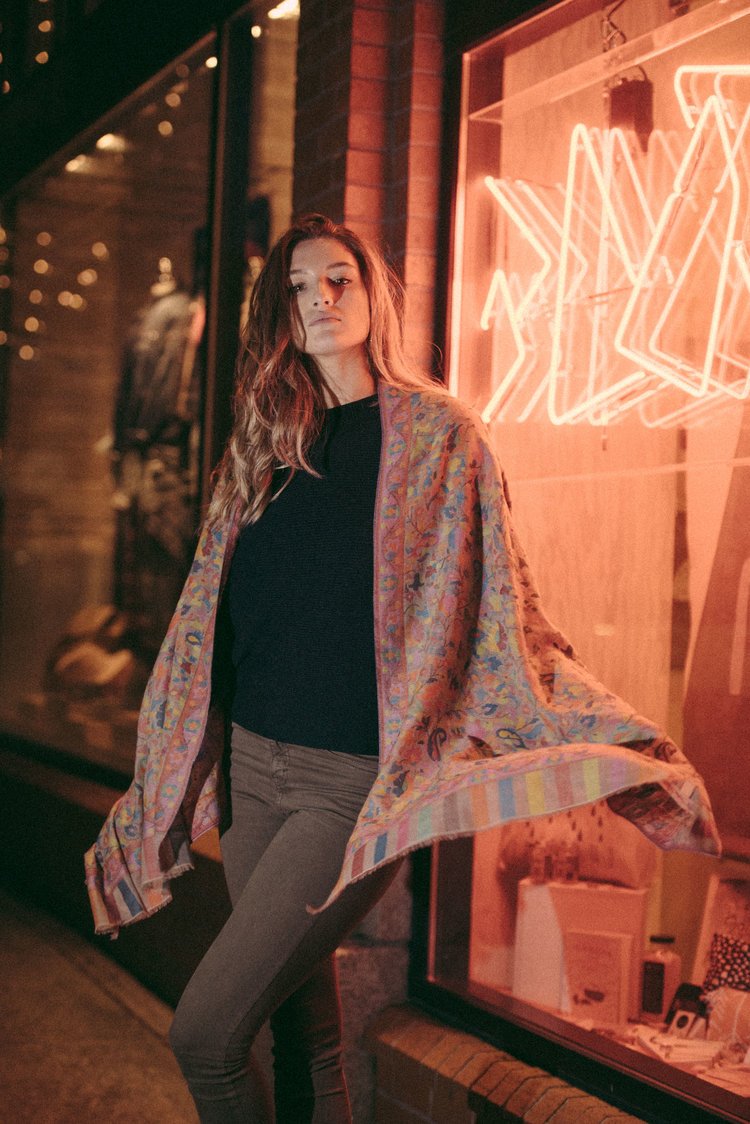 A fashion lifestyle photographer captures a woman in a vibrant shawl posing in front of a store.jpg