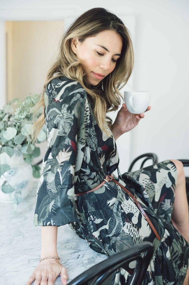 A lifestyle photographer photographed a woman sitting on a chair, holding a cup of coffee while wearing a designer dress..jpg