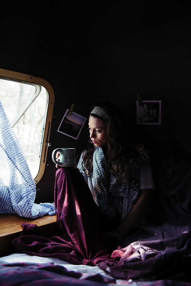 A woman enjoying a cup of coffee while sitting in bed, captured by a travel lifestyle photographer.jpg