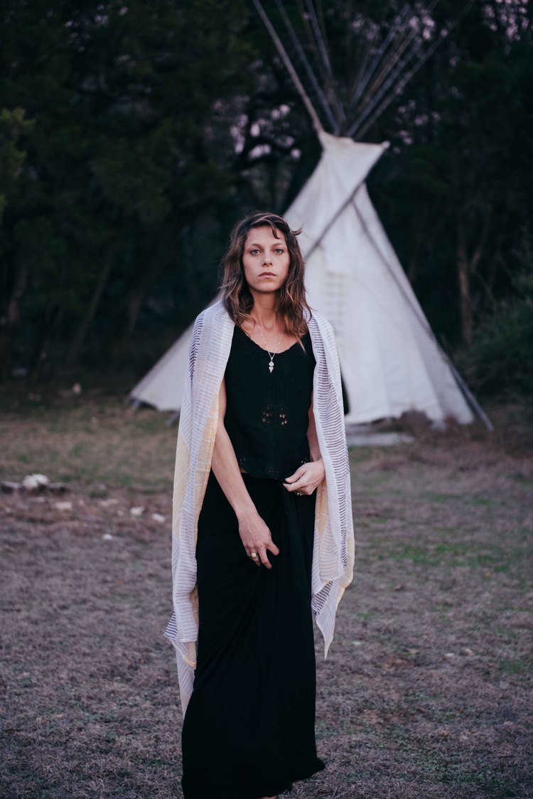 A woman in a black dress posing in front of a teepee, capturing the essence of the travel lifestyle photography.jpg