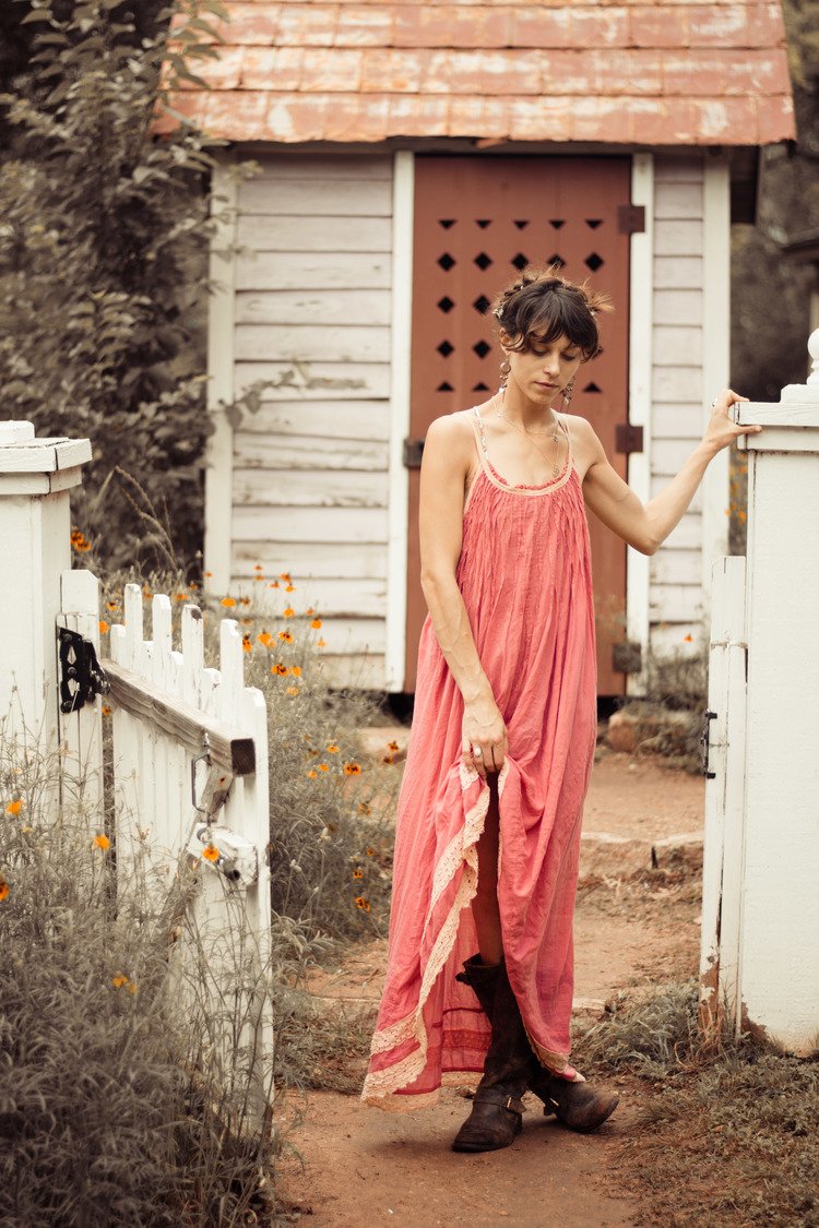 A woman in a pink dress posing in front of a white house. Captured by a Portland lifestyle portrait photographer.jpg