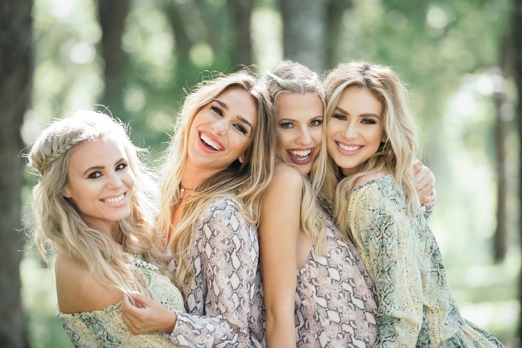 Four women in matching dresses Joyfully smiling in camera, enjoying a leisurely lifestyle together.jpg