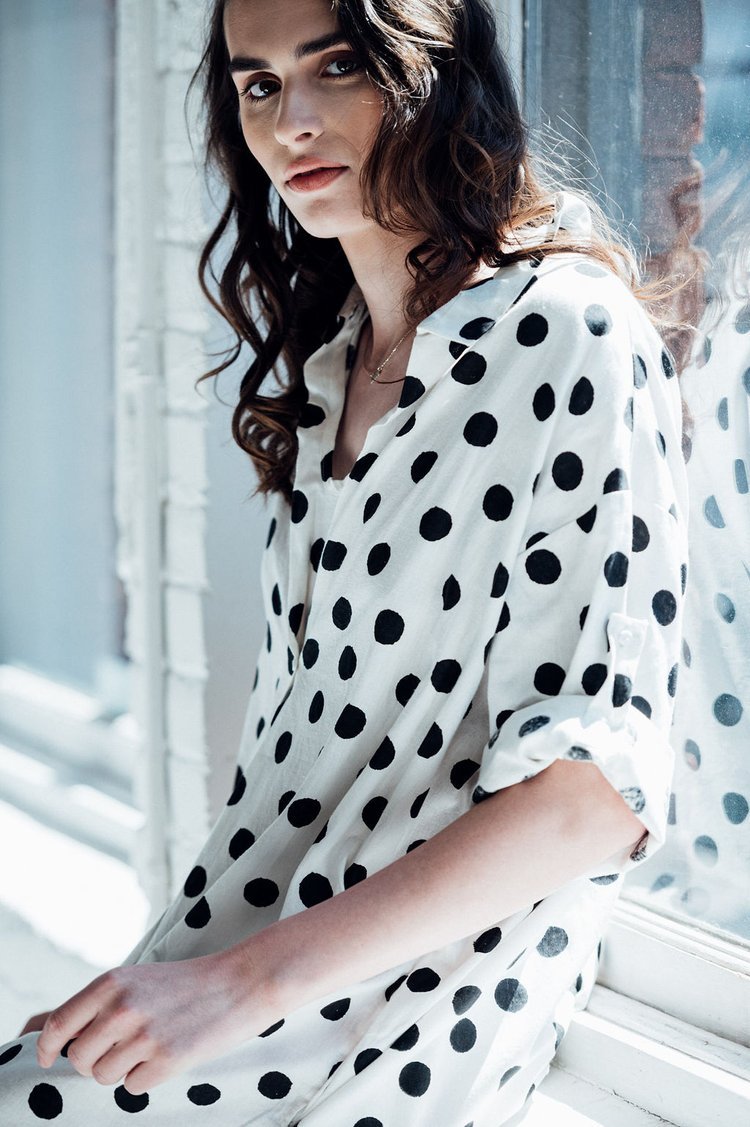 a woman sitting on a window sill wearing a polka dot dress for an editorial.jpg