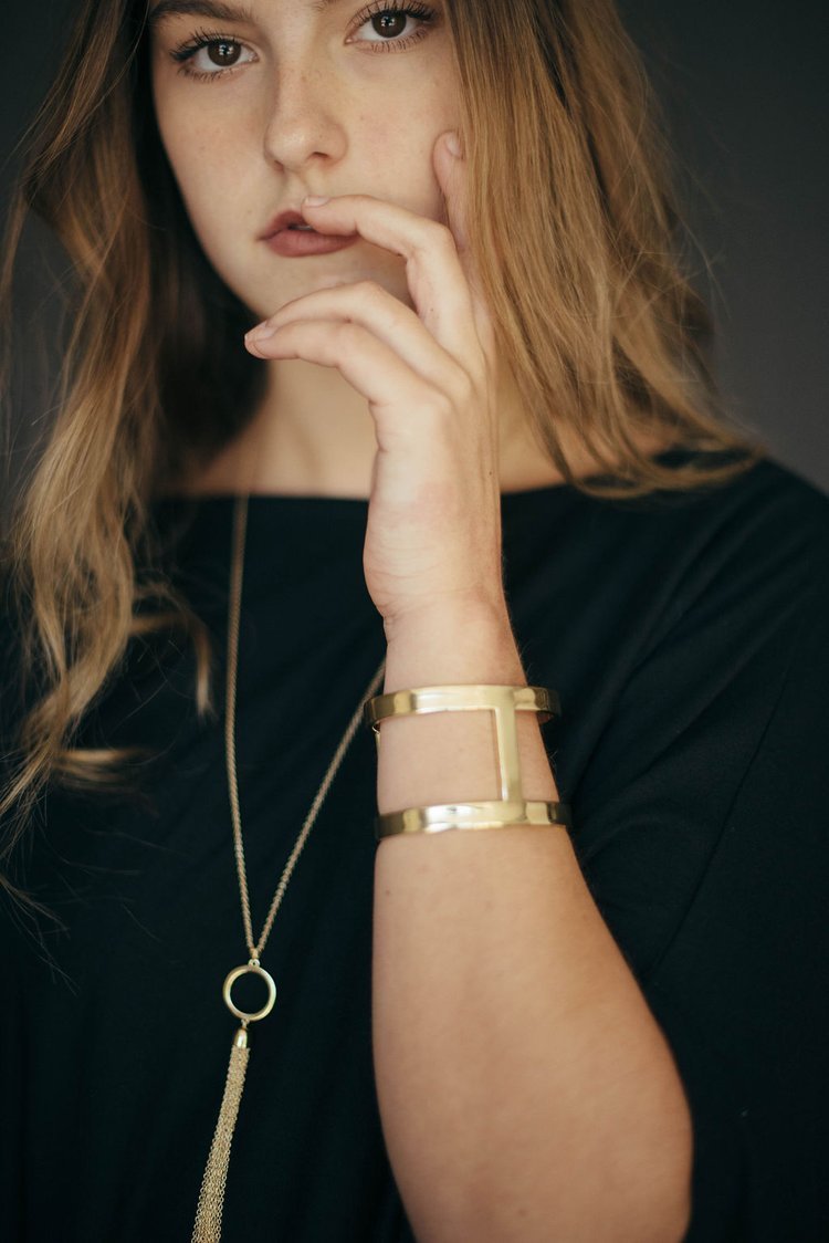 An editorial photographer captures a female model adorned in a black shirt and a gold bracelet..jpg