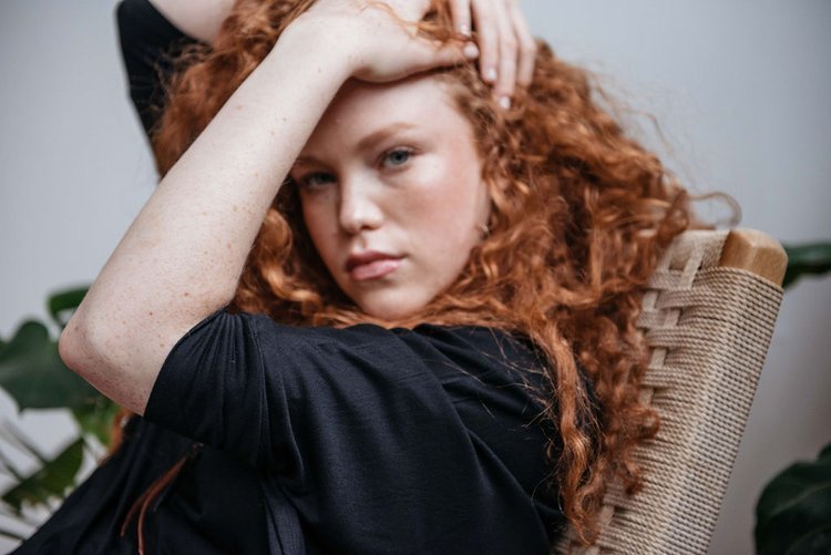 Editorial photographer captures a girl with red hair seated in a wicker chair..jpg