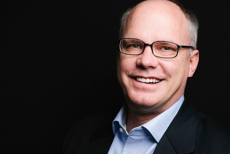 A professional business headshot featuring a bald man in glasses and a blue shirt, available in Portland.jpg