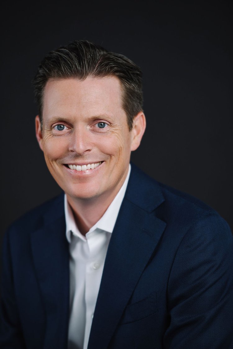 A professional businessman in Portland posing for corporate headshots, wearing a suit and with a friendly smile.jpg