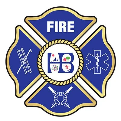 Portrait of a smiling firefighter in uniform against a black background, showing badge, patch, and name tag.