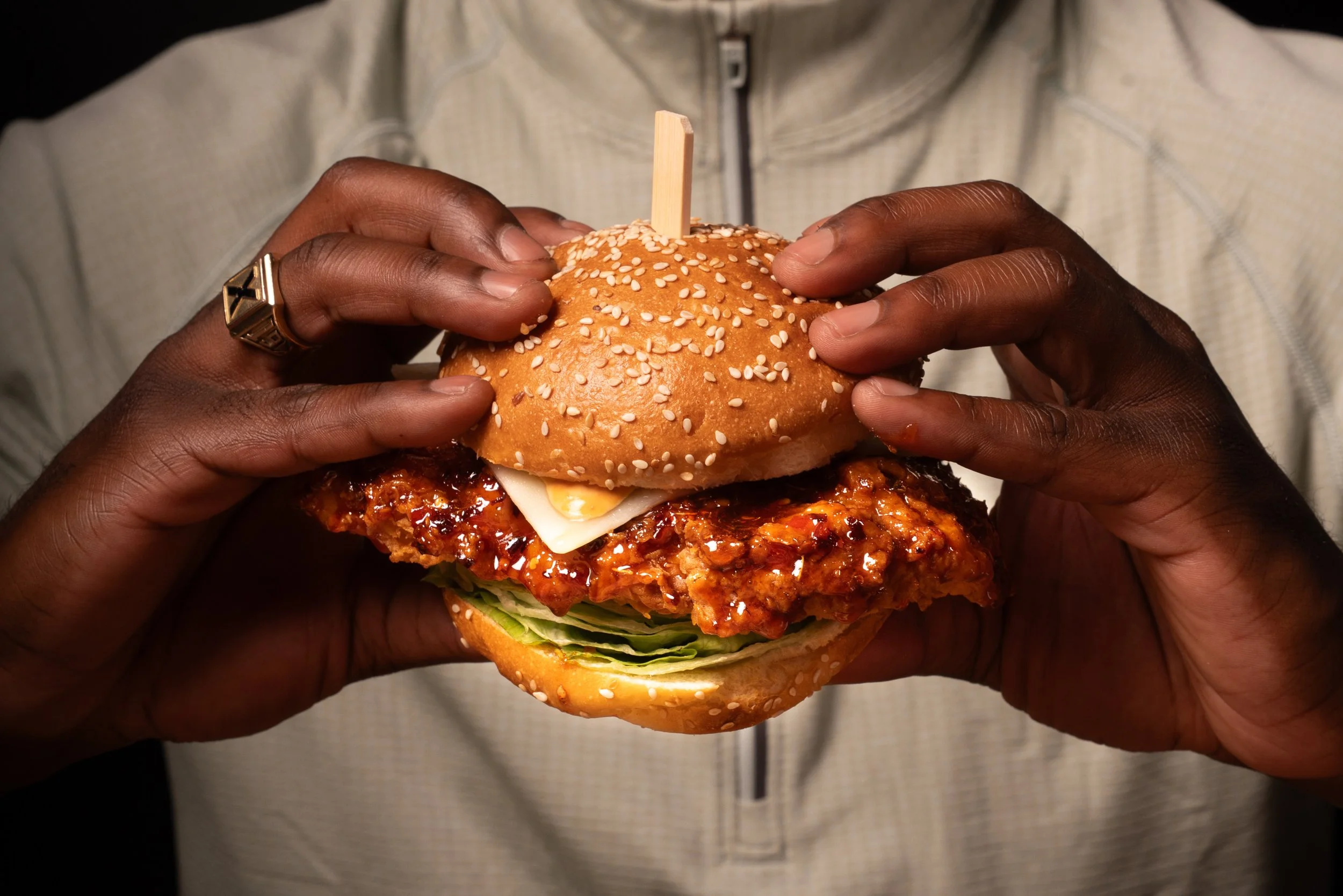 Hot Honey Chicken Burger: buttermilk brined crispy chicken, hot honey glaze, iceberg lettuce, pickles, burnt chili aoili, monterey jack, served on a sesame potato brioche bun (choice of fries or house salad)