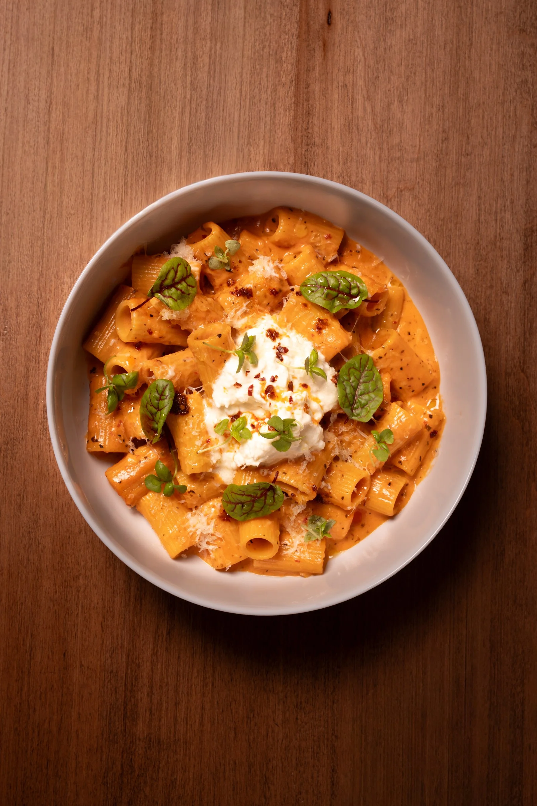 Spicy Rigatoni: vodka rose sauce, stracciatella cheese, house made chili garlic oil, parmesan cheese, micro basil 