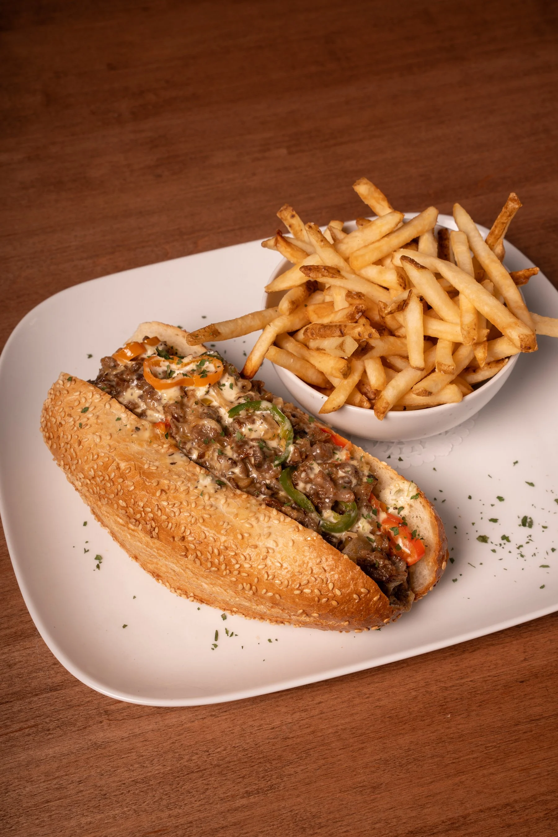 B+B Cheesesteak: thinly sliced AAA Alberta beef, caramelized onions, sweet peppers, jalapenos, aged white cheddar, jalapeno-parmesan sauce, toasted sesame demi-baguette (choice of fries or house salad)