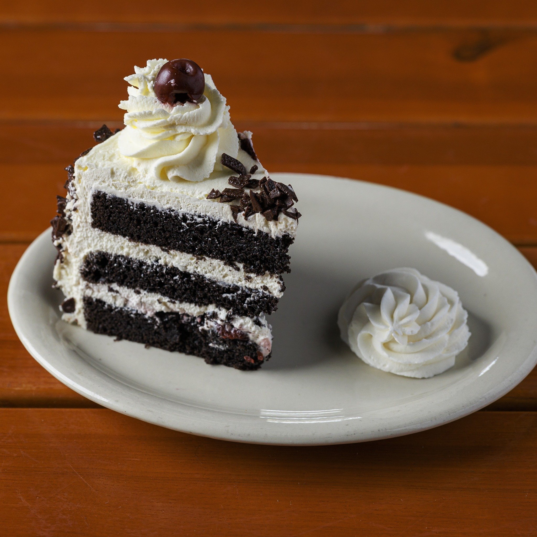 𝐒𝐜𝐡𝐰𝐚𝐫𝐳𝐰𝐚̈𝐥𝐝𝐞𝐫 𝐊𝐢𝐫𝐬𝐜𝐡𝐭𝐨𝐫𝐭𝐞!
Hollerbach's Black Forest Cake is made by our own pastry chefs with decadent rich chocolate cake, homemade whipped cream, cherry baking Schnapps (Kirsch), dark cherries soaked in Kirsch, dark chocol