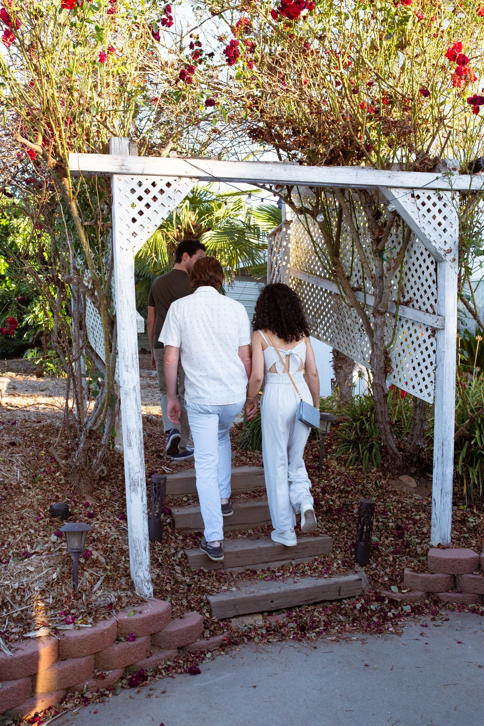 3 people walking through the rose arch