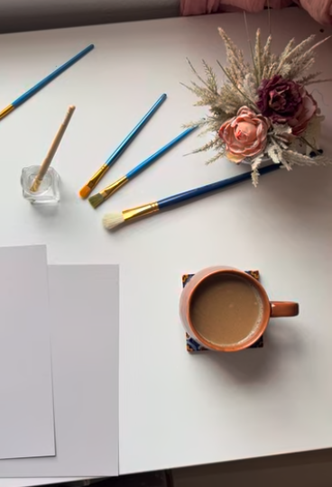 resident setup with painting supplies with a latte and flowers on a desk